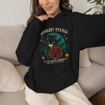 Person wearing a hoodie with a black cat with a red rose and golden stars graphic on the front