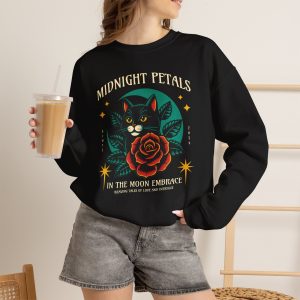 Person wearing a crewneck sweatshirt with a black cat with a red rose and golden stars graphic on the front