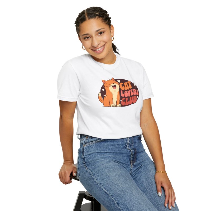 Person wearing a tee with a smiling orange tabby beside retro lettering in an oval badge with hearts and starbursts printed on the front