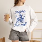Person wearing a sweatshirt with a blue cat on a bicycle