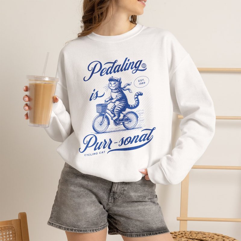 Person wearing a sweatshirt with a blue cat on a bicycle
