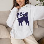 Person wearing a hoodie with a navy arched cat and wavy lettering graphic on the front