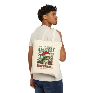 Person carrying a natural canvas tote with the Santa-hat kitten with holly and an ornament graphic facing outward