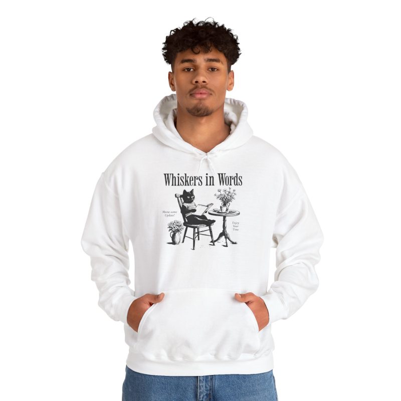Person wearing a hoodie with a cat reading a book at a café table graphic on the front
