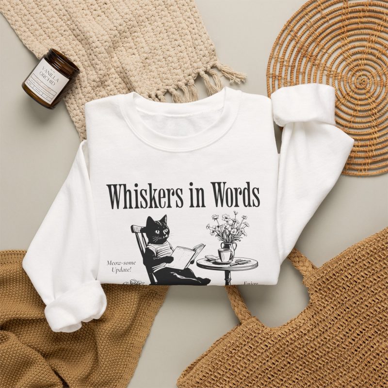 Detail of the cat reading a book at a café table graphic on the crewneck sweatshirt