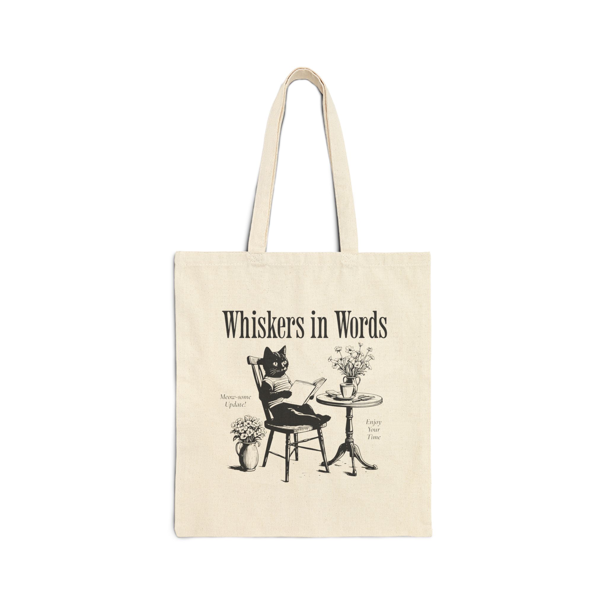 Front of the natural canvas tote showing the cat reading a book at a café table graphic