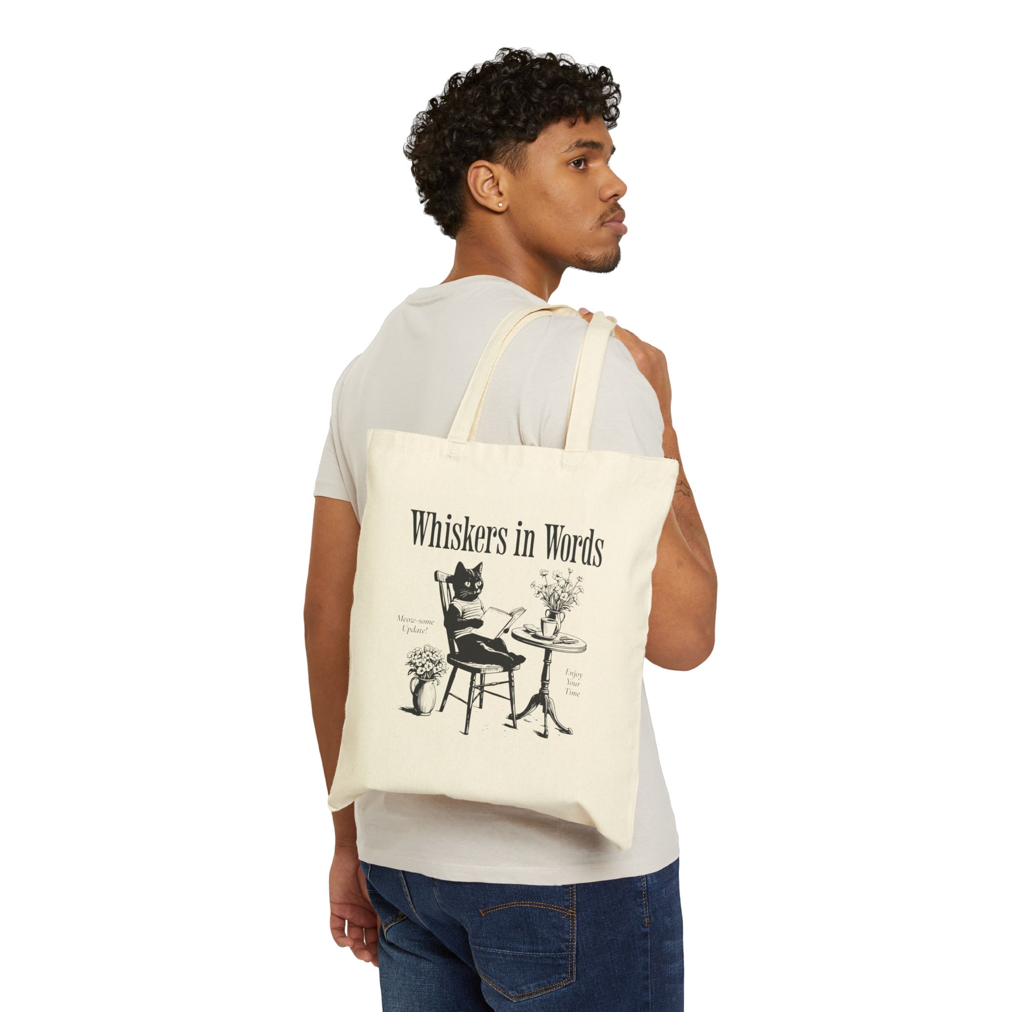 Person carrying a natural canvas tote with the cat reading a book at a café table graphic facing outward