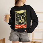 Person wearing a sweatshirt with a bold cat portrait and red panel