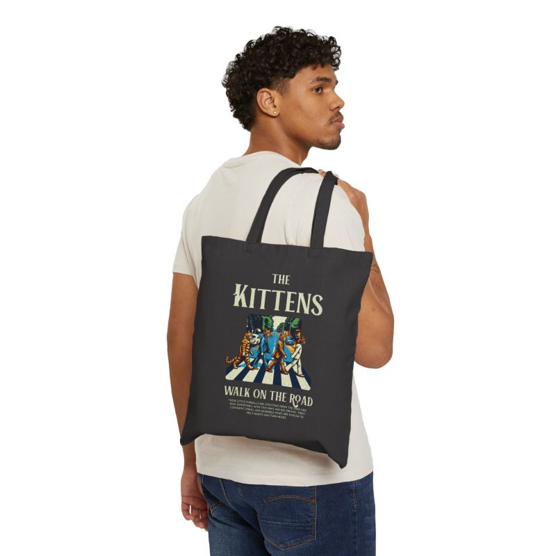 Person carrying a black canvas tote with crosswalk kittens