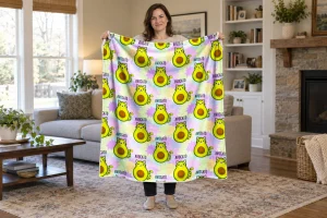 Woman holding the full Avocato cat blanket open in a light living room, showing green avocado cats and pastel stars repeated edge to edge.