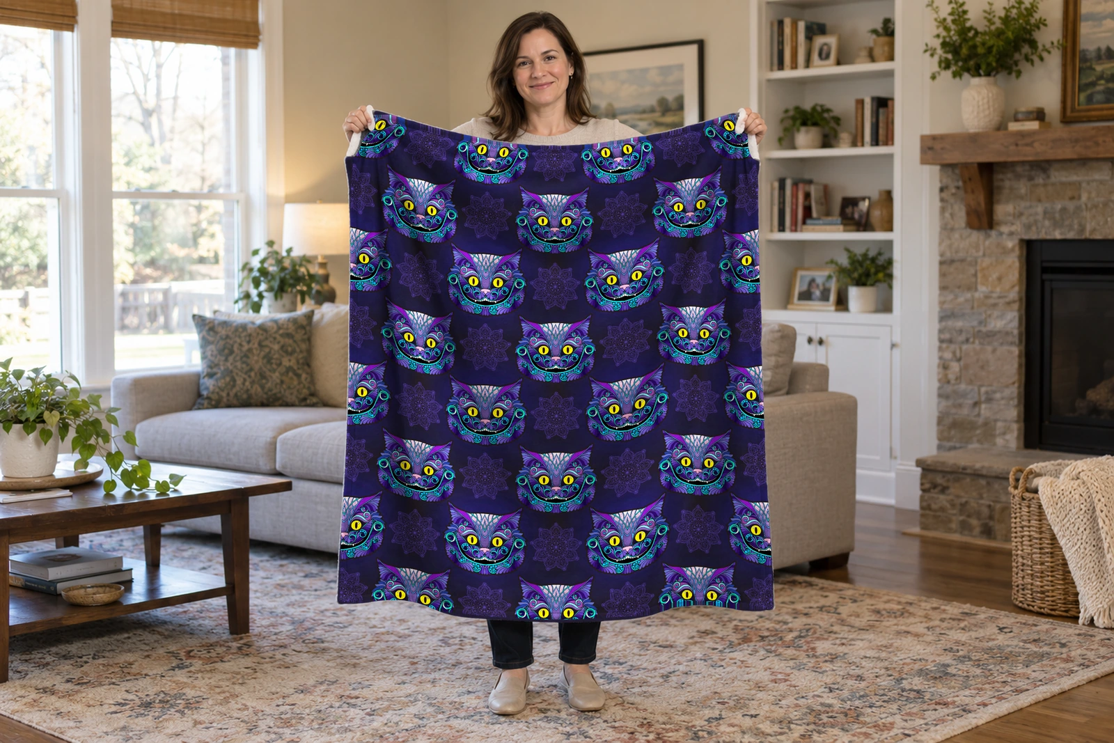 Woman holding open a purple cat flannel blanket with smiling purple and turquoise faces, yellow eyes, and faint mandalas on midnight blue.