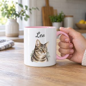 Hand holding a personalized cat mug with a pink handle and interior, a watercolor tabby cat portrait and the name Leo